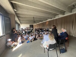 Foto della sala dell'evento con i vari alunni e le insegnanti che hanno preso parte al progetto.